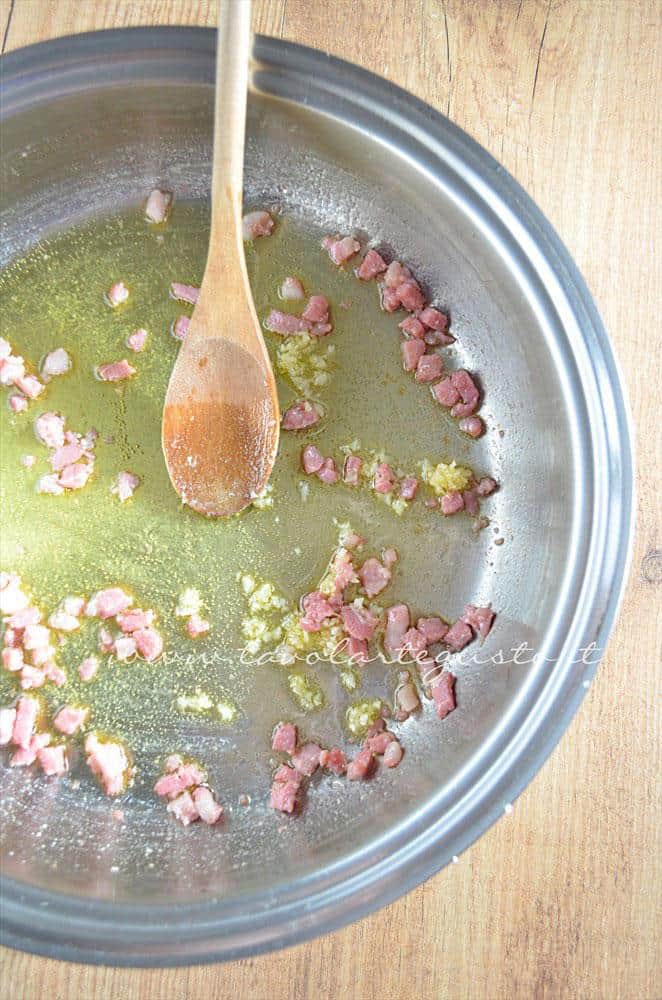 Aggiungere l'aglio al soffritto di olio e pancetta - Ricetta Bordura di riso con crema di carciofi e crostini di Fiore Sardo Aggiungere l'aglio al soffritto di olio e pancetta - Ricetta Bordura di riso con crema di carciofi e crostini di Fiore Sardo