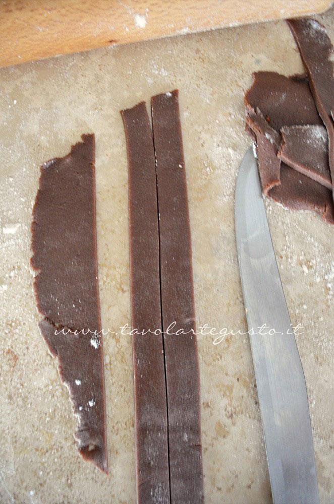 Realizzare delle strisce sottili di pasta frolla al cacao - Ricetta Crostata morbida al cioccolato Realizzare delle strisce sottili di pasta frolla al cacao - Ricetta Crostata morbida al cioccolato
