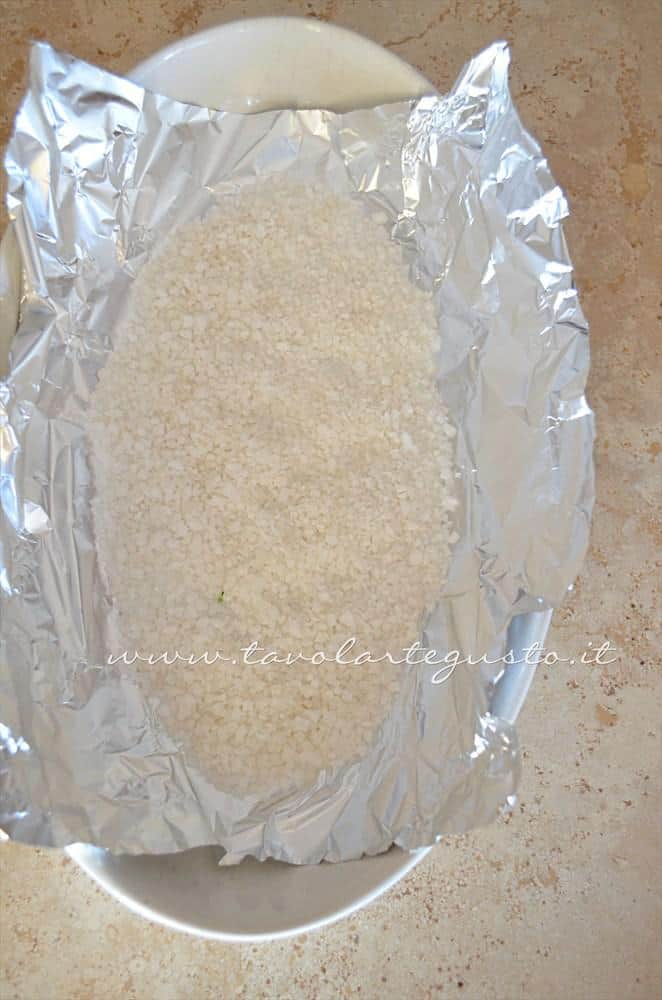 Adagiare il sale grosso sul fondo del foglio allumino - Ricetta Branzino al sale Adagiare il sale grosso sul fondo del foglio allumino - Ricetta Branzino al sale