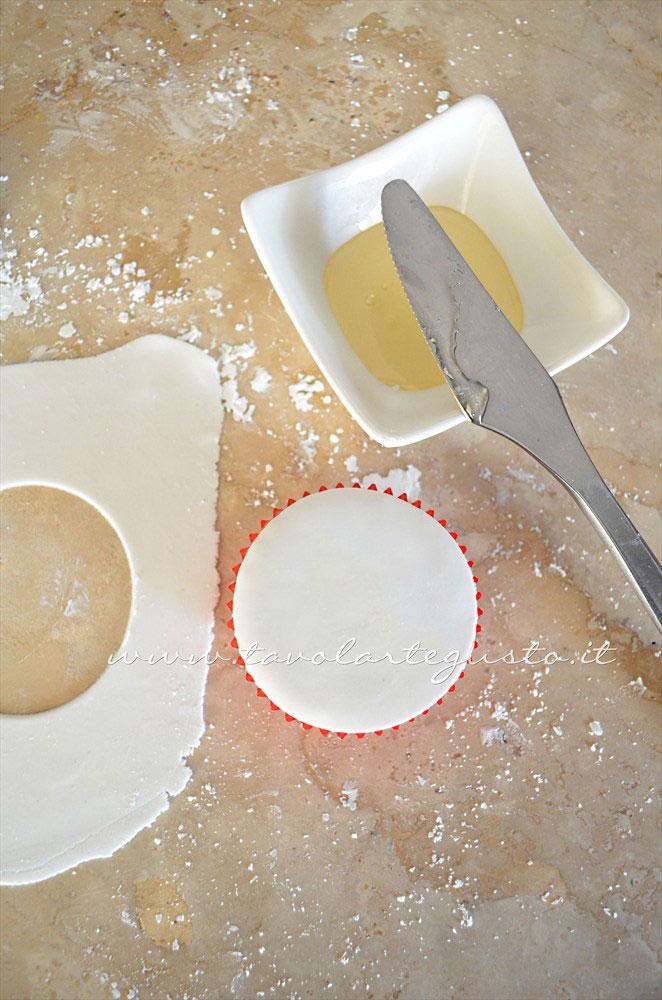 Adagiare sulla tortina il cerchio di pasta di zucchero - Ricetta Cupcakes Natalizi decorati in Pasta di Zucchero - Cupcakes di Natale Adagiare sulla tortina il cerchio di pasta di zucchero - Ricetta Cupcakes Natalizi decorati in Pasta di Zucchero - Cupcakes di Natale