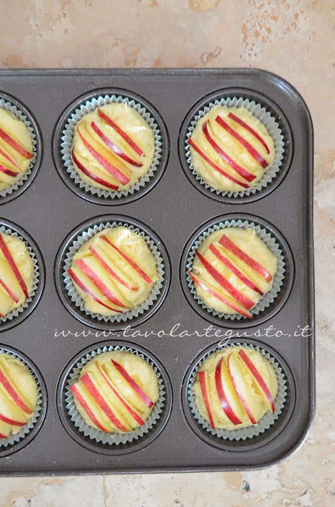 Adagiare impasto nei pirottini e fettine di mela nei muffins - Ricetta Muffins ricotta e mele Adagiare impasto nei pirottini e fettine di mela nei muffins - Ricetta Muffins ricotta e mele