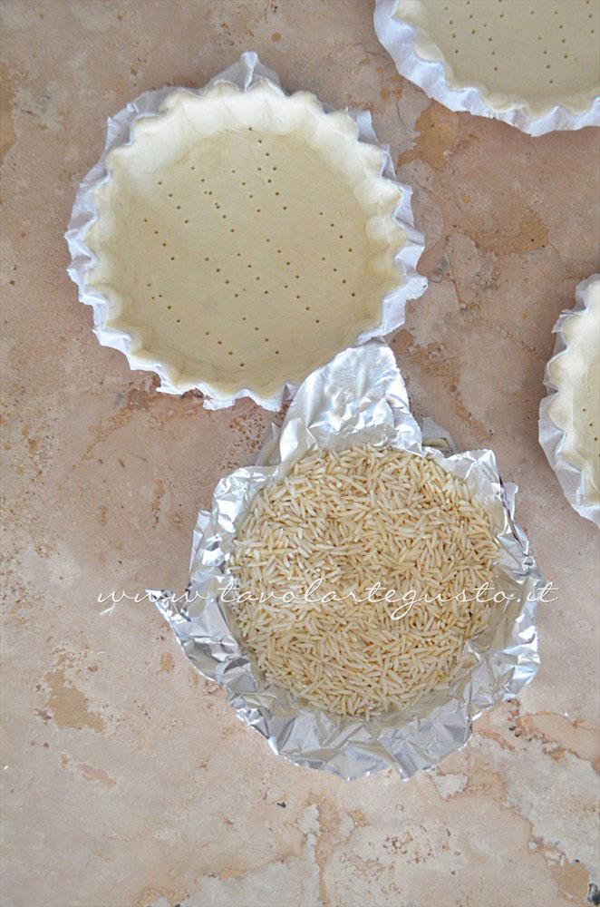 Inserire la pasta sfoglia negli stampi e preparare per la cottura in bianco - Ricetta Crostatine di pasta sfoglia alle due creme e frutti rossi