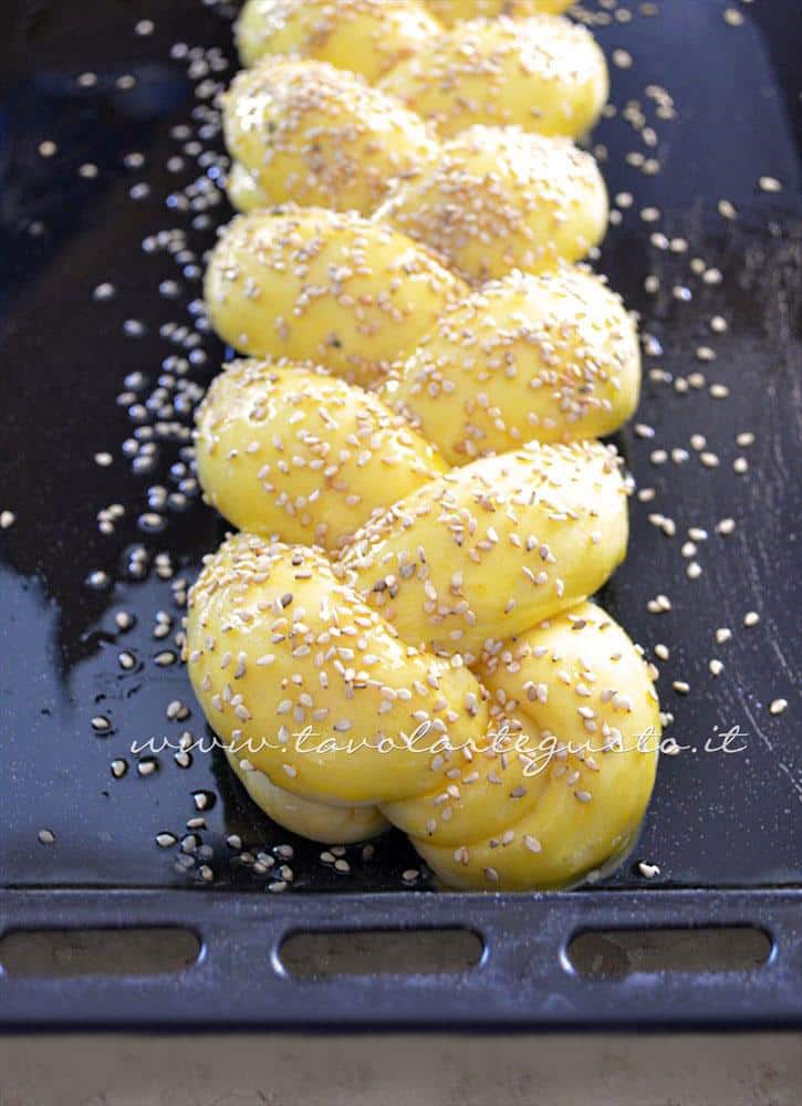 Treccia lievitata, pennellata d'uovo e semi di sesamo, pronta per essere infornata - Ricetta Pan Brioche senza burro - Pan Brioche all'olio Treccia lievitata, pennellata d'uovo e semi di sesamo, pronta per essere infornata - Ricetta Pan Brioche senza burro - Pan Brioche all'olio