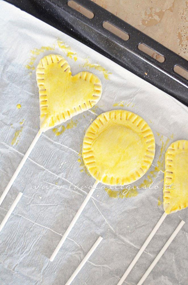 Pennellare la superficie dei lecca lecca con un tuorlo sbattuto - Ricetta Lecca lecca salati di pasta sfoglia Pennellare la superficie dei lecca lecca con un tuorlo sbattuto - Ricetta Lecca lecca salati di pasta sfoglia