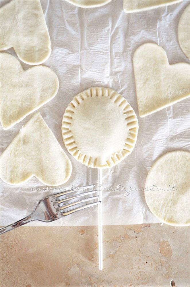 Sigillare i bordi dei lecca lecca con i rebbi di una forchetta - Ricetta Lecca lecca salati di pasta sfoglia Sigillare i bordi dei lecca lecca con i rebbi di una forchetta - Ricetta Lecca lecca salati di pasta sfoglia
