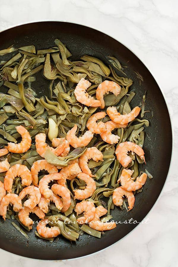Aggiungere i gamberi ai carciofi in padella - Ricetta Pasta risottata con carciofi, gamberi e pepe rosa Aggiungere i gamberi ai carciofi in padella - Ricetta Pasta carciofi e gamberi