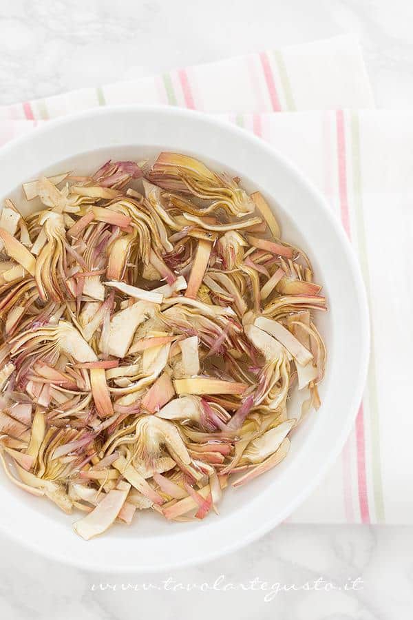 Pulire i carciofi e metterli in acqua fredda - Ricetta Pasta risottata con carciofi, gamberi e pepe rosa Pulire i carciofi e metterli in acqua fredda - Ricetta Pasta carciofi e gamberi