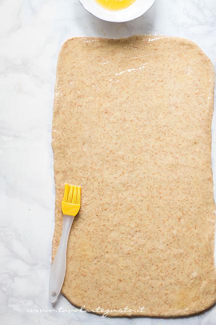 Stendere metà impasto e pennellarlo di burro fuso - Ricetta Cornetti Integrali al miele